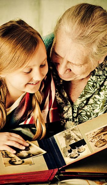 Great-grandmother shows old photos (these are pictures of her and her grandmather) to her great-granddaughter.